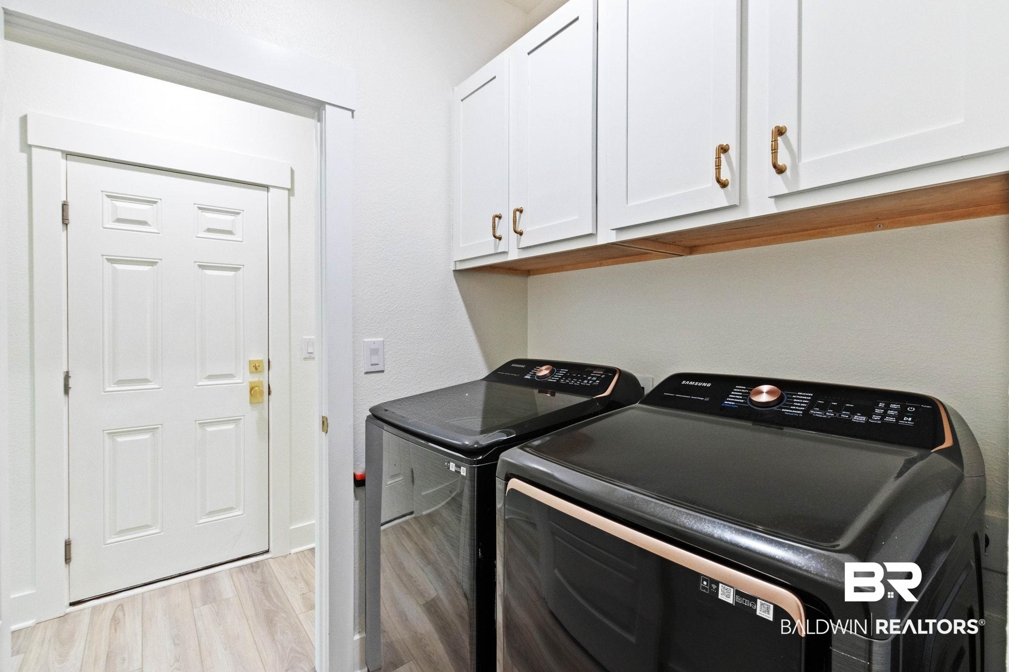 9815 Lakeview Drive Foley, AL 36535 - Photo 55 of 100 Laundry room with light hardwood / wood-style flooring, washing machine and dryer, and cabinets