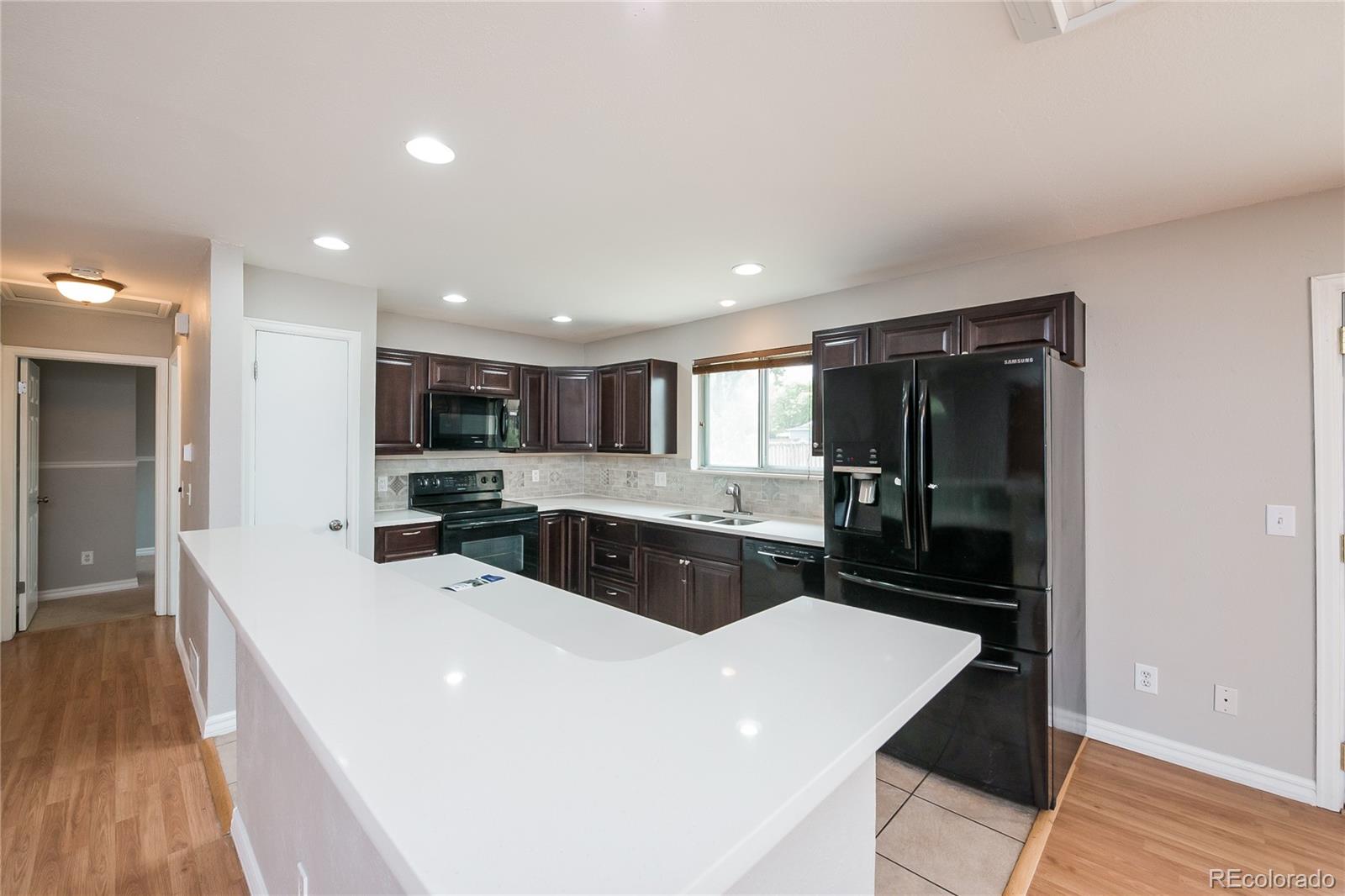 11103 Eudora Circle Thornton, CO 80233 - Photo 4 of 17 a large white kitchen with a large counter top space a sink and stainless steel appliances