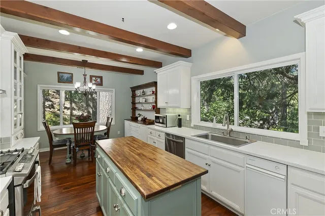 a kitchen with a stove a sink a counter top space and living room view