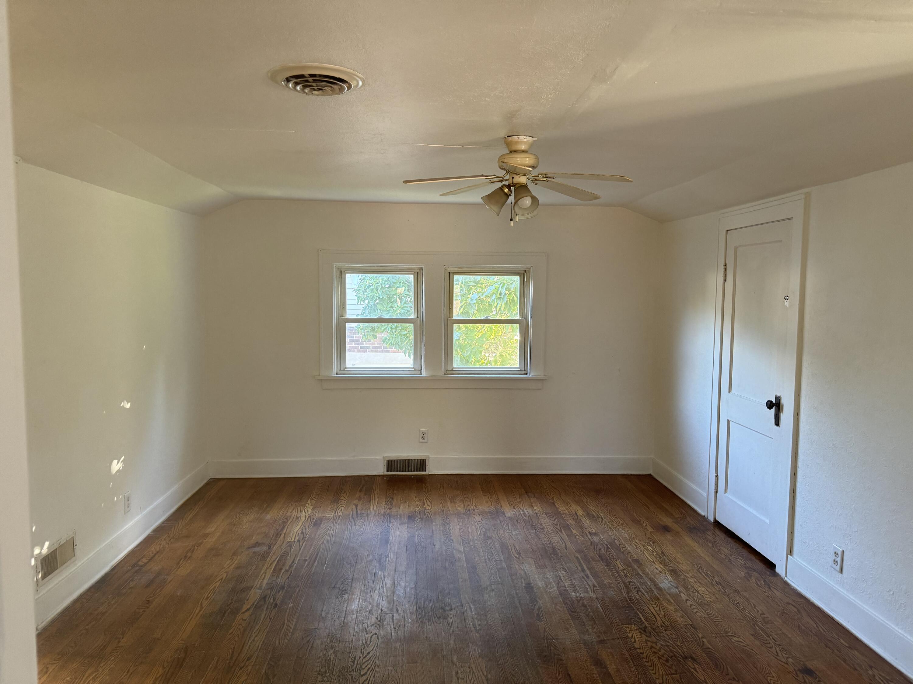217 West Ripley Street Michigan City, IN 46360 - Photo 9 of 28 an empty room with wooden floor chandelier fan and windows
