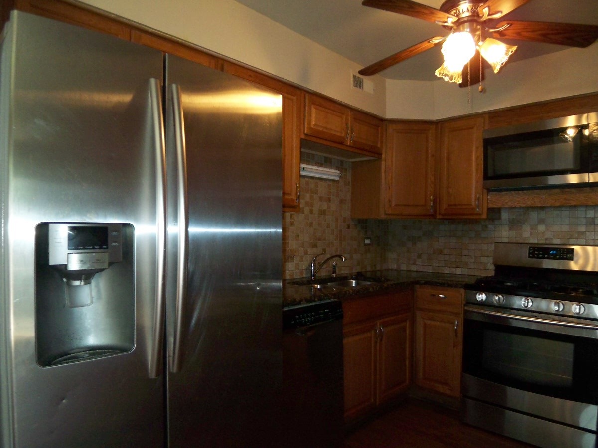 1925 Georgetown Lane Hoffman Estates, IL 60169 - Photo 7 of 29 a kitchen with stainless steel appliances granite countertop a refrigerator a stove and a sink with wooden floor