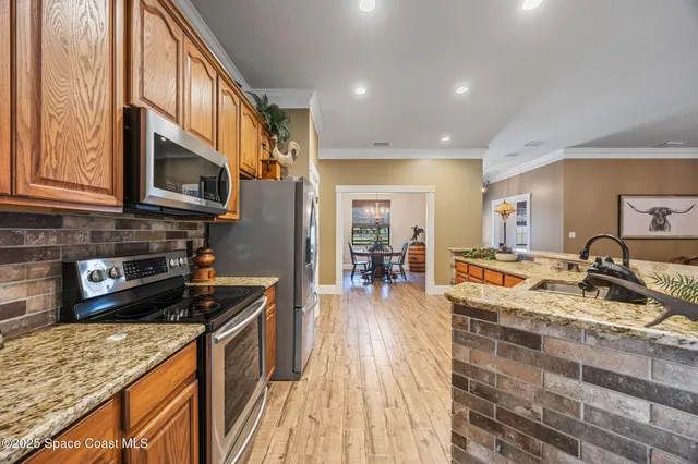 a kitchen with stainless steel appliances granite countertop a stove a sink a microwave and living room