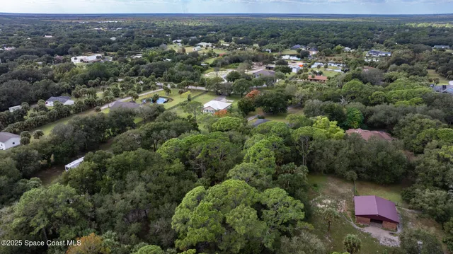 an aerial view of residential houses with outdoor space and trees