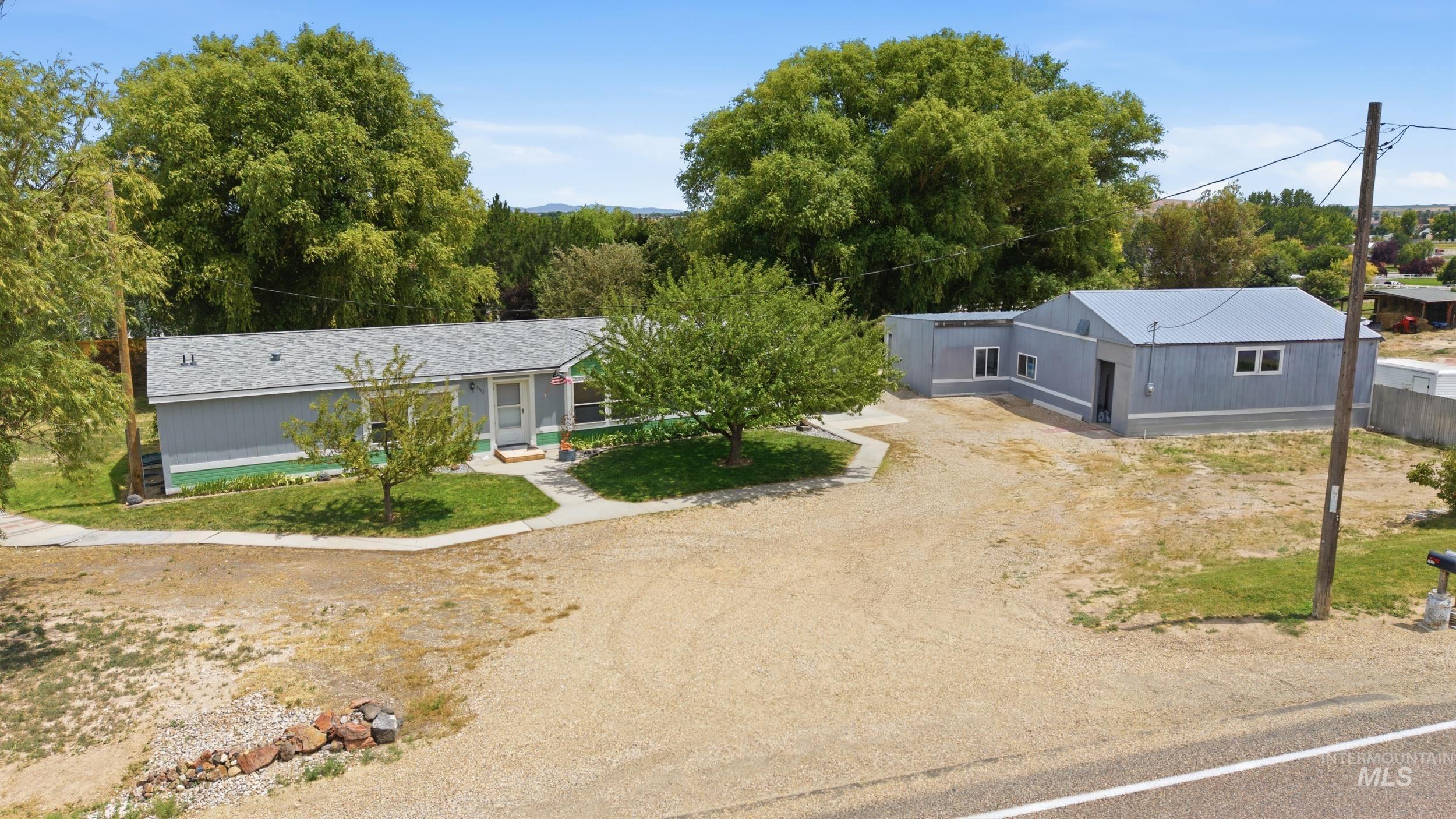 7422 Track Road Nampa, ID 83686 - Photo 2 of 50 Single-story residence with a light gray exterior and green trim, featuring a concrete walkway