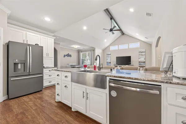 a kitchen with stainless steel appliances granite countertop a sink refrigerator and cabinets