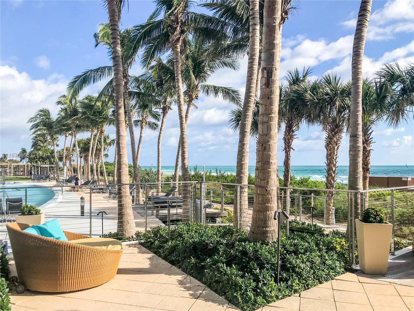 6799 Collins Avenue, Unit 1601 Miami Beach, FL 33141 - Photo 35 of 64 a view of a swimming pool with a lawn chairs and palm tree