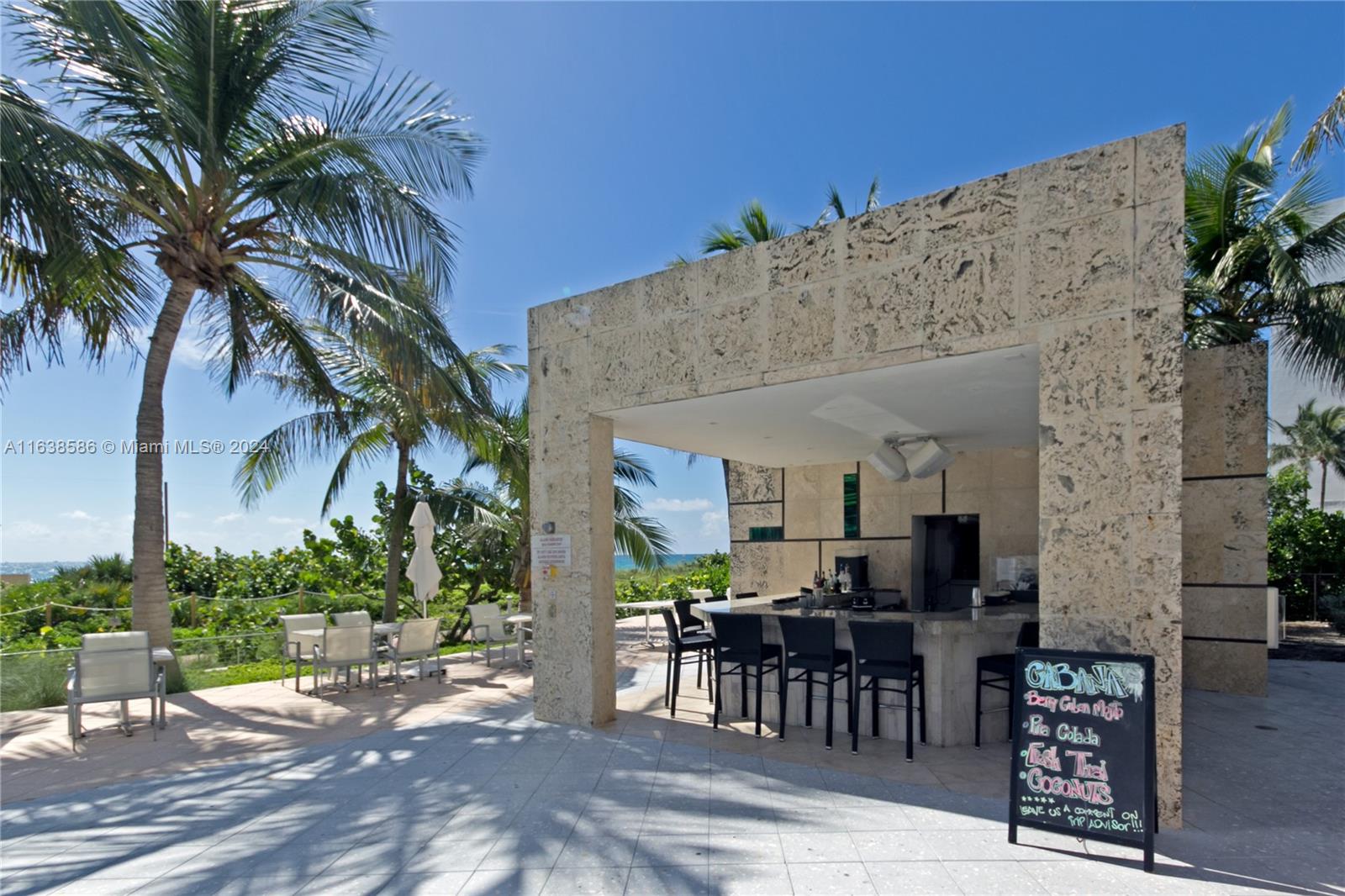 6799 Collins Avenue, Unit 1601 Miami Beach, FL 33141 - Photo 56 of 64 a view of a patio with table and chairs potted plants and palm tree
