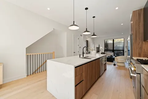 a kitchen with stainless steel appliances a stove a sink a center island a dining table and chairs