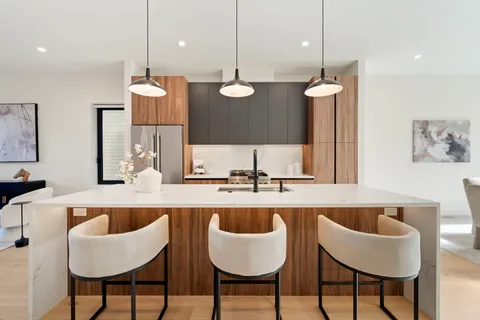 a kitchen with granite countertop kitchen island stainless steel appliances living room and chairs