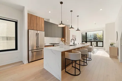 a kitchen with stainless steel appliances granite countertop a refrigerator a sink a stove a dining table and chairs