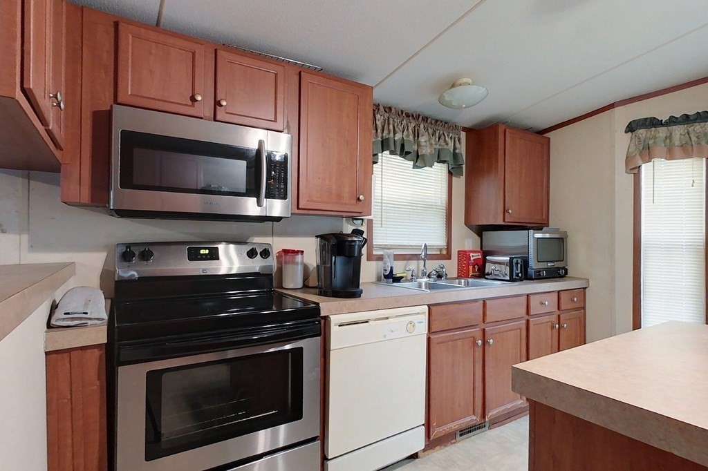 11 Groton School Road, Unit 2 Ayer, MA 01432 - Photo 3 of 14 a kitchen with cabinets stainless steel appliances a sink and a counter space