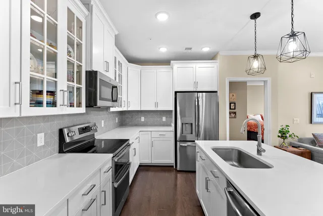 a kitchen with a sink a stove a refrigerator and white cabinets