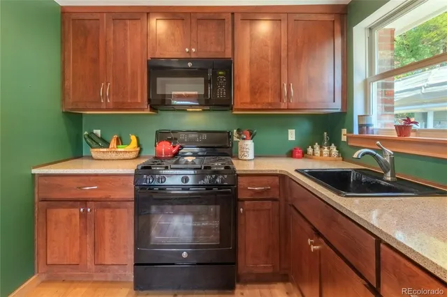 a kitchen with granite countertop wood cabinets stainless steel appliances and a sink