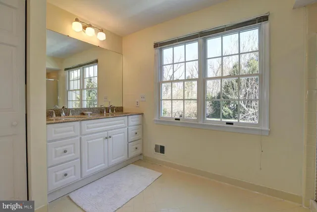a spacious bathroom with a granite countertop sink mirror and a next to a window