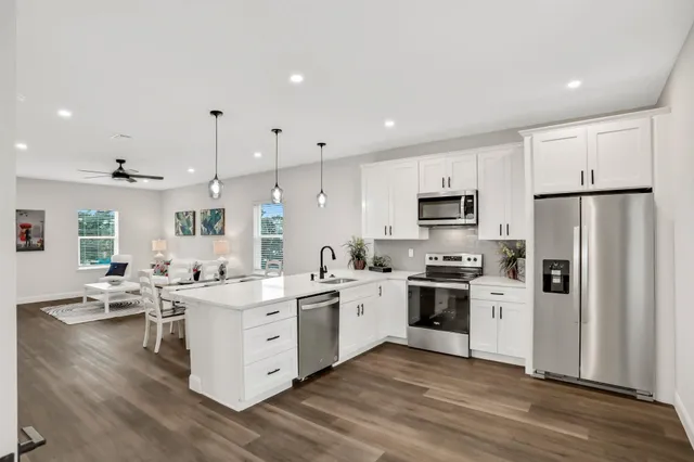 a kitchen with stainless steel appliances a sink a refrigerator a center island a stove a microwave and cabinets