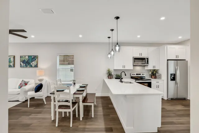 a kitchen with stainless steel appliances kitchen island granite countertop a dining table chairs stove refrigerator and microwave