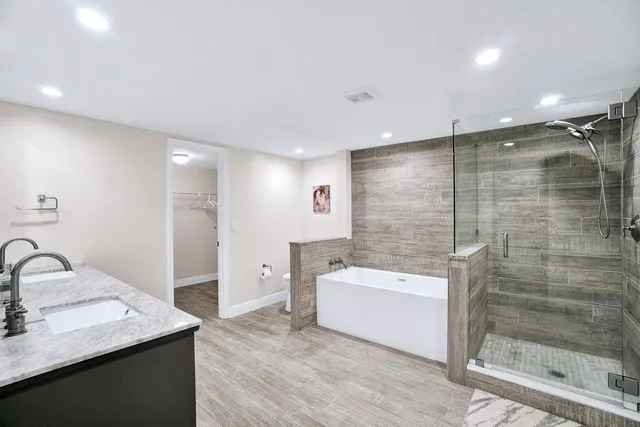 a bathroom with a bathtub shower sink vanity and toilet
