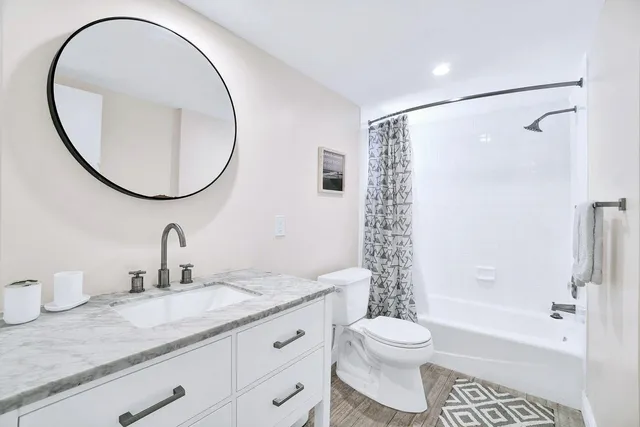 a bathroom with a granite countertop sink toilet a mirror and a shower