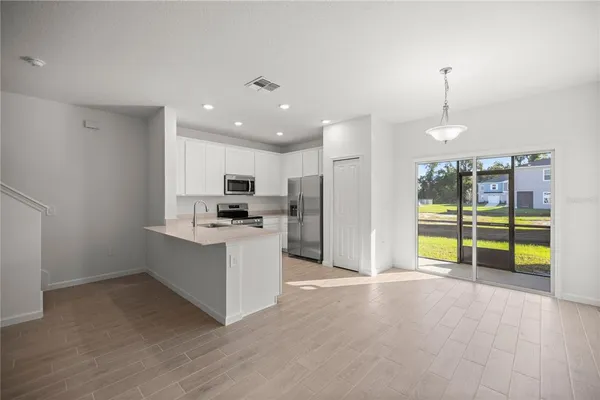 a view of kitchen with stainless steel appliances kitchen island wooden floor and living room view
