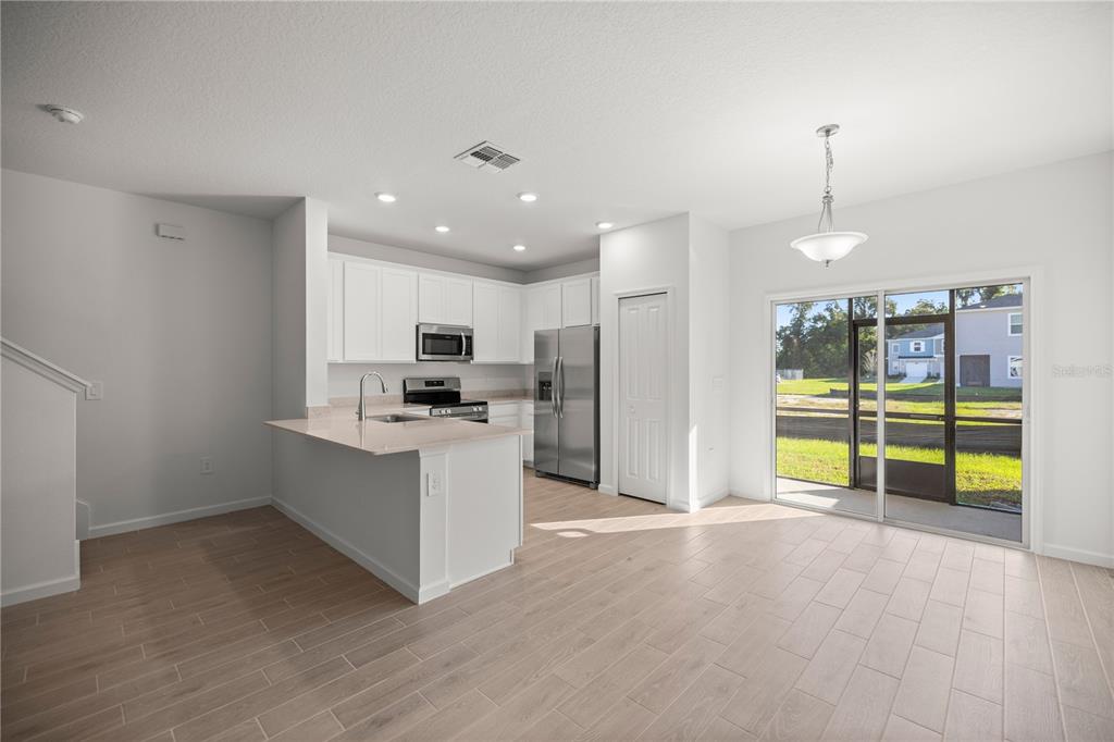 a view of kitchen with stainless steel appliances kitchen island wooden floor and living room view