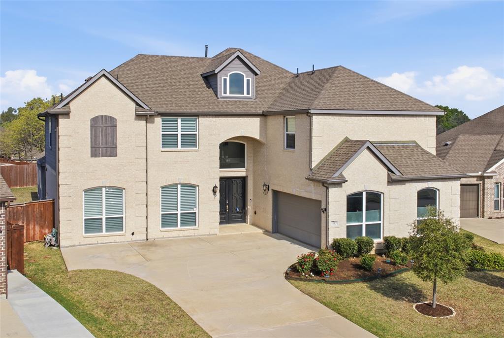 View of front facade with a shingled roof, driveway, and a garage