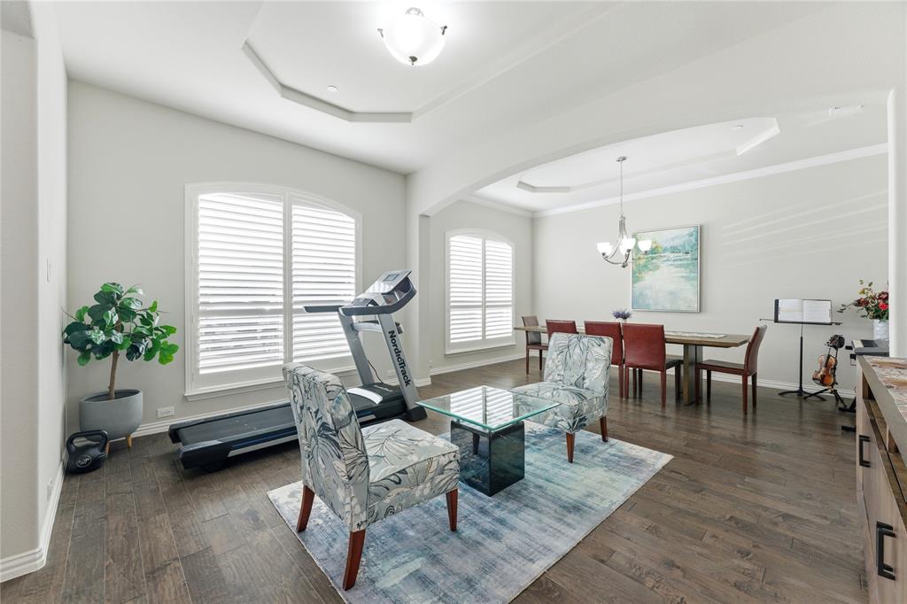 7705 Falcon Ridge Road Denton, TX 76208 - Photo 13 of 40 Dining space featuring a tray ceiling, hanging lights, arched walkways, dark wood finished floors, and crown molding