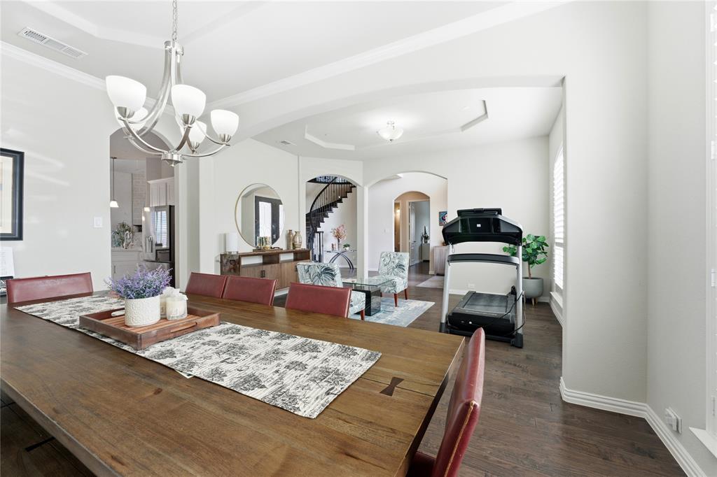 7705 Falcon Ridge Road Denton, TX 76208 - Photo 14 of 40 Dining space featuring a tray ceiling, hanging lights, arched walkways, dark wood finished floors, and crown molding