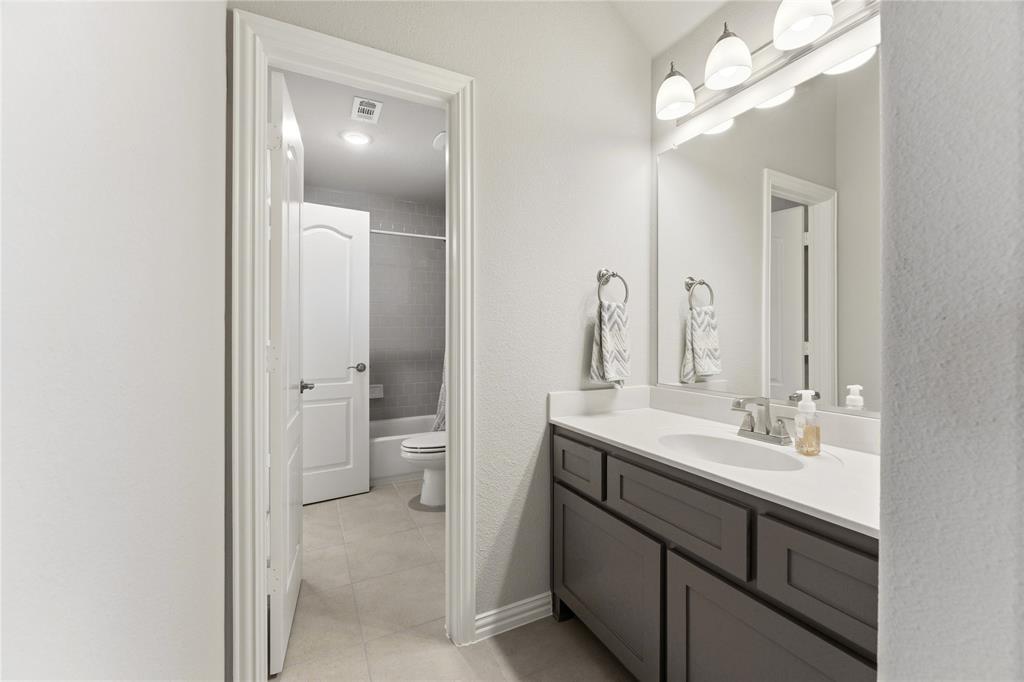 7705 Falcon Ridge Road Denton, TX 76208 - Photo 35 of 40 Bathroom featuring vanity, light tile patterned floors, and shower / tub combo with curtain