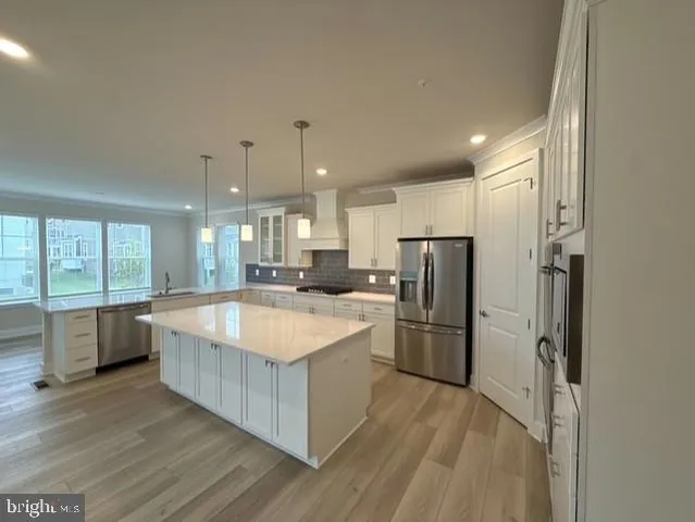 a large kitchen with a center island wooden floor stainless steel appliances and windows