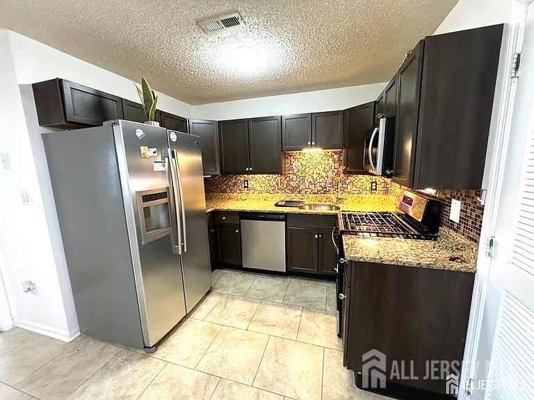 a kitchen with stainless steel appliances granite countertop a refrigerator and a stove