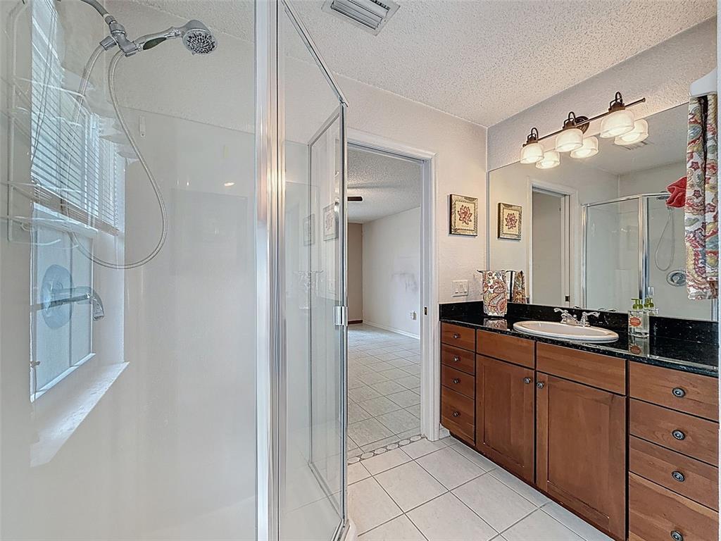 9545 Montebello Lane Spring Hill, FL 34608 - Photo 34 of 74 a bathroom with a granite countertop sink mirror and a shower