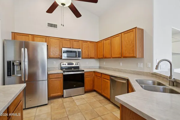 a living room with stainless steel appliances furniture a flat screen tv and kitchen view