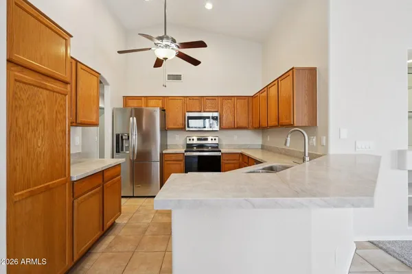 a kitchen with stainless steel appliances granite countertop a sink a stove top oven a refrigerator with island and chairs