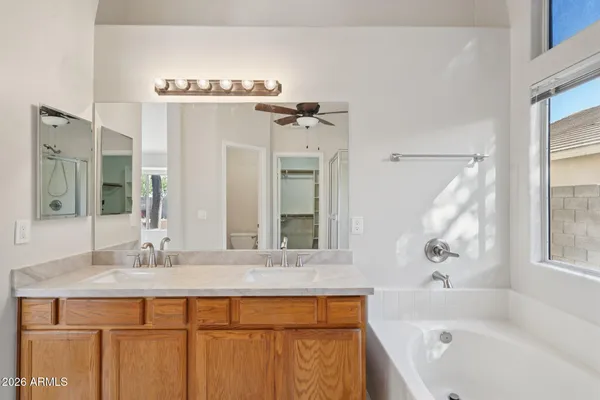 a bathroom with a granite countertop sink a mirror a bathtub and shower