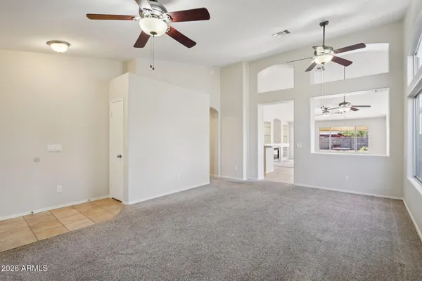 an empty room with chandelier fan and windows