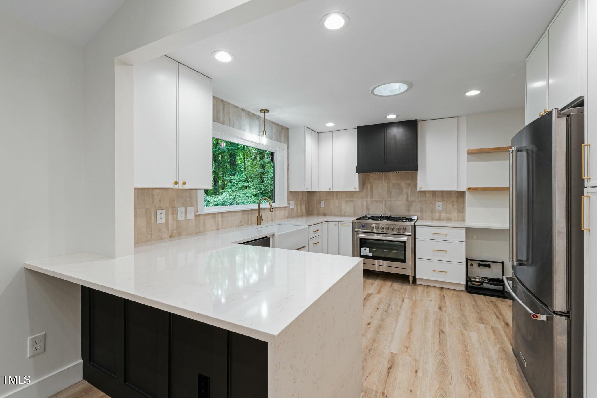 6421 Arrington Road Raleigh, NC 27607 - Photo 5 of 31 a kitchen with a sink a counter top space stainless steel appliances and cabinets