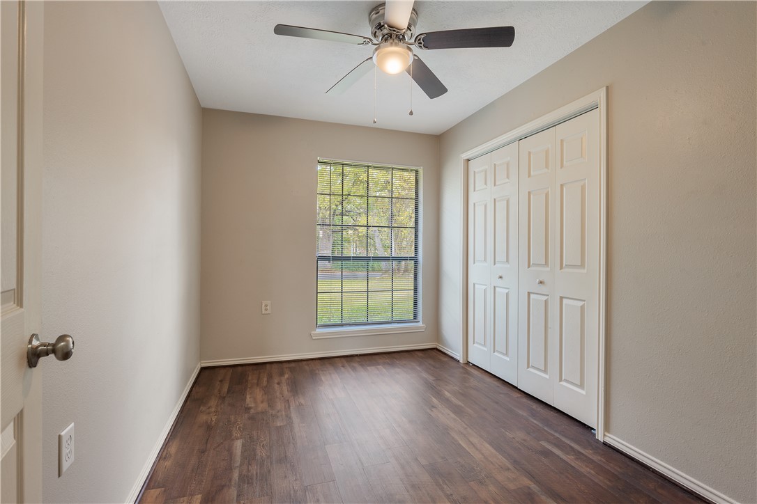 1003 East 24th Street Bryan, TX 77803 - Photo 15 of 24 Unfurnished bedroom with dark wood-style floors, a ceiling fan, and a closet