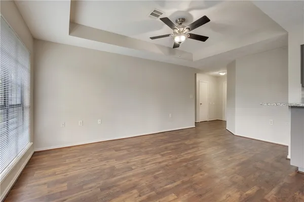an empty room with wooden floor and ceiling fan
