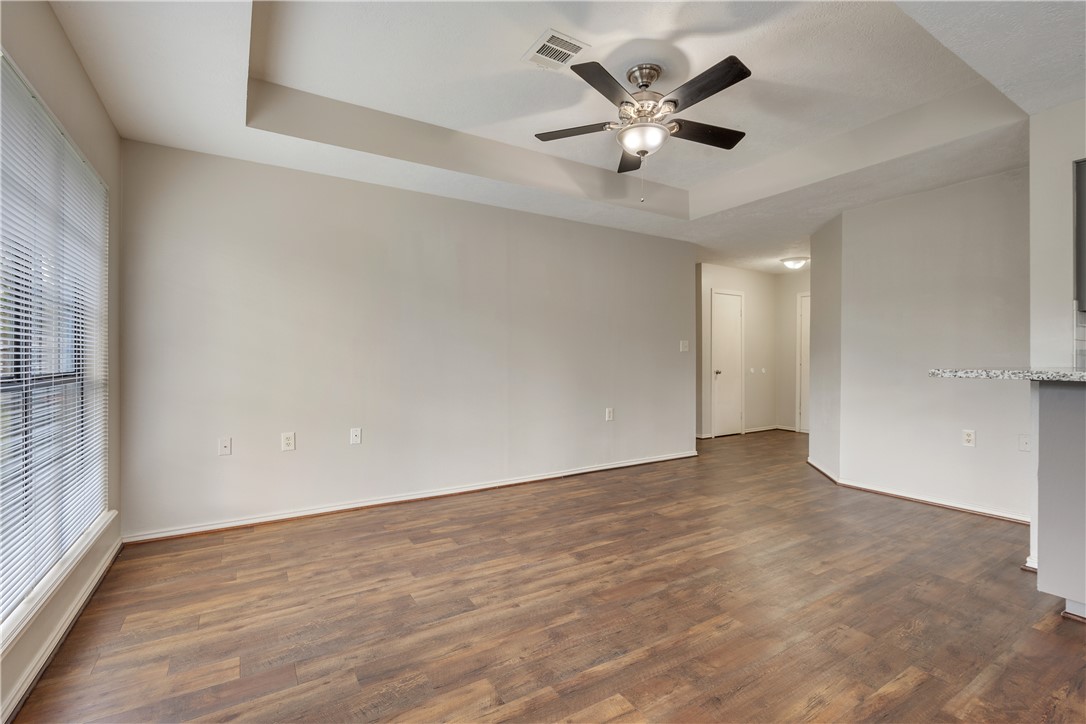 1003 East 24th Street Bryan, TX 77803 - Photo 5 of 24 Unfurnished room with a raised ceiling, dark wood-type flooring, and ceiling fan