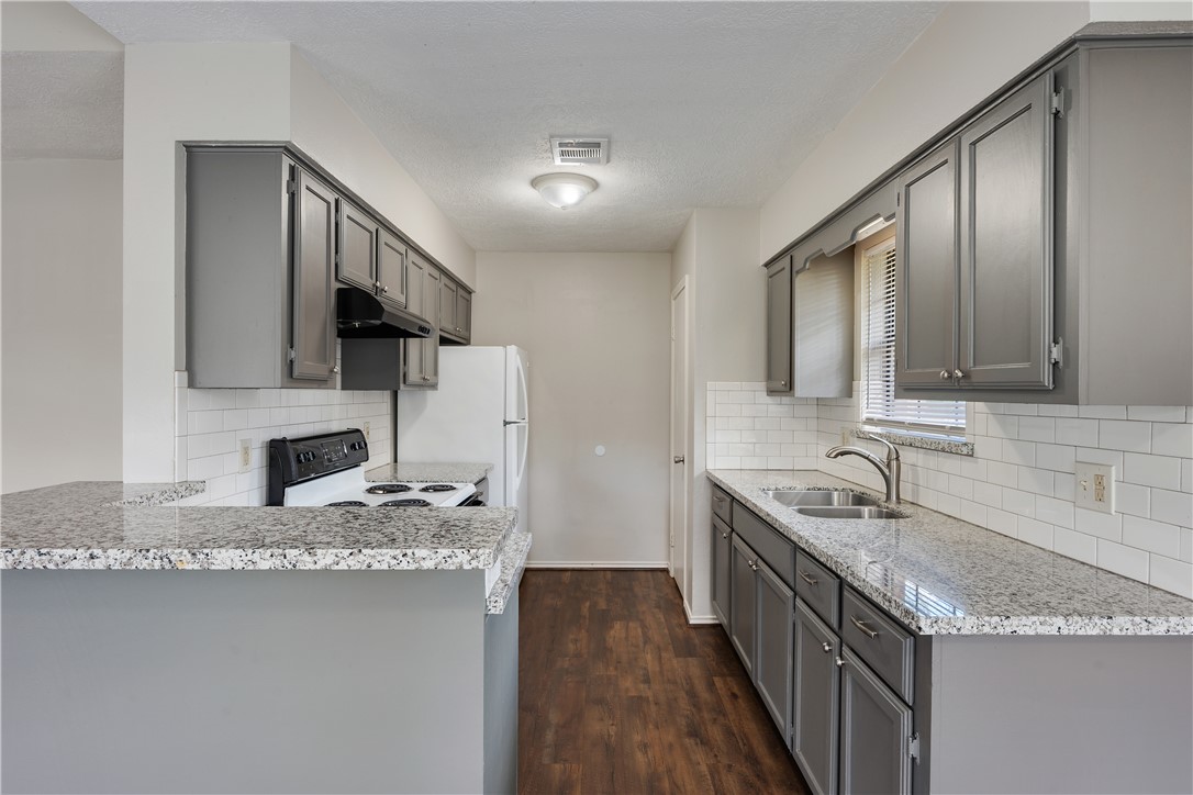 1003 East 24th Street Bryan, TX 77803 - Photo 9 of 24 Kitchen featuring gray cabinets, dark wood-type flooring, white electric range, decorative backsplash, and a textured ceiling