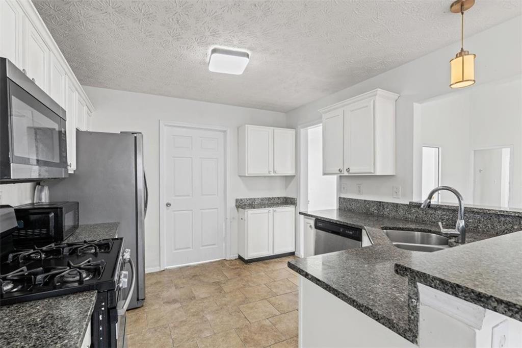 109 Enclave Court Powder Springs, GA 30127 - Photo 7 of 40 a kitchen with stainless steel appliances granite countertop a sink stove and refrigerator