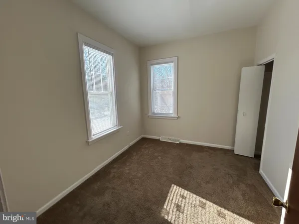 a view of an empty room with closet and a window