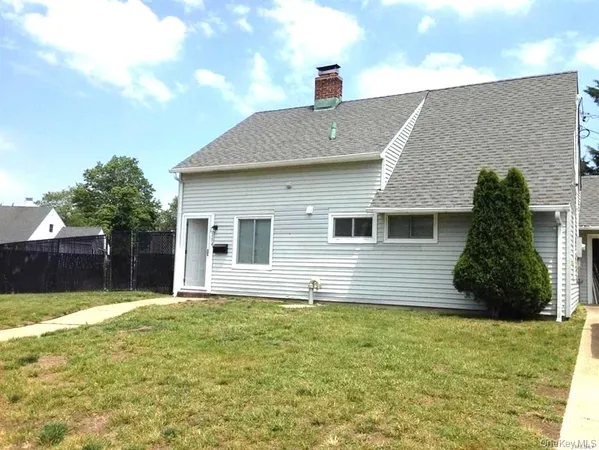 a front view of house with yard and trees in the background