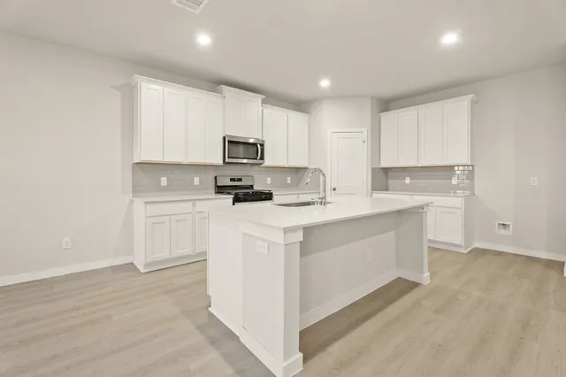 a kitchen with kitchen island a white cabinets and refrigerator