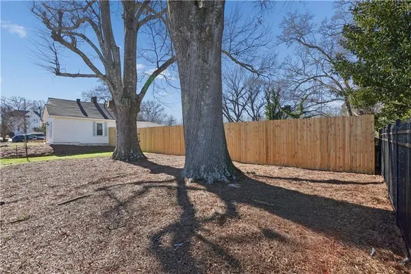 a backyard of a building with trees and a wooden fence
