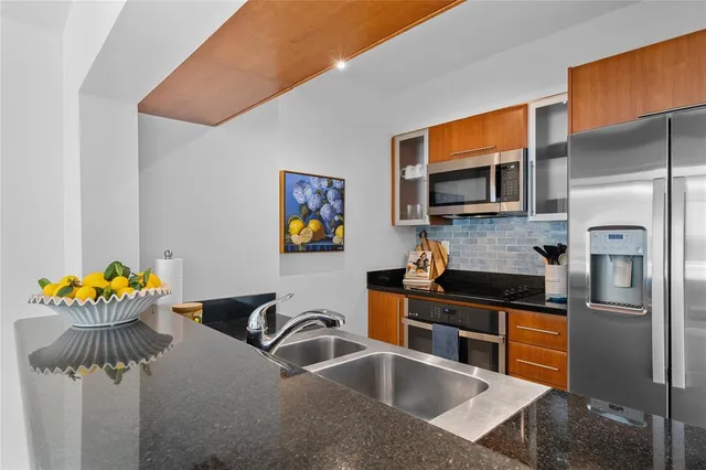 a kitchen with stainless steel appliances granite countertop a sink a stove and a refrigerator