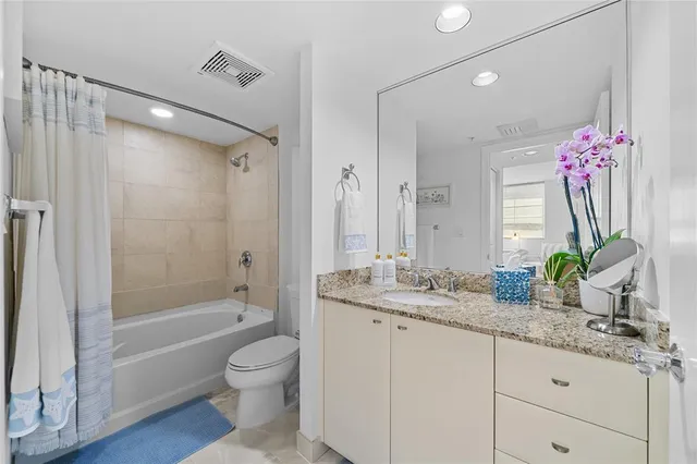 a bathroom with a granite countertop sink a toilet a mirror and shower