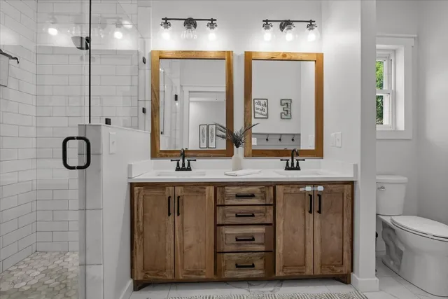 a bathroom with a double vanity sink a large mirror and a shower