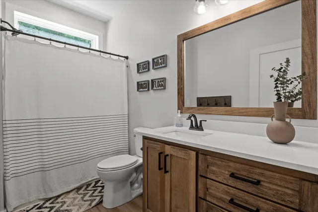 a bathroom with a granite countertop sink toilet and mirror