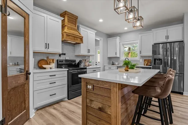 a kitchen with stainless steel appliances granite countertop a sink a stove a refrigerator cabinets and a dining table